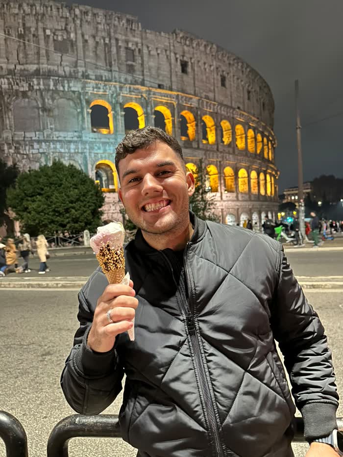 Alexandre com um gelato diante do Coliseu iluminado à noite
