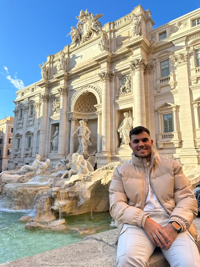 Alexandre sentado na borda da Fontana di Trevi, em Roma